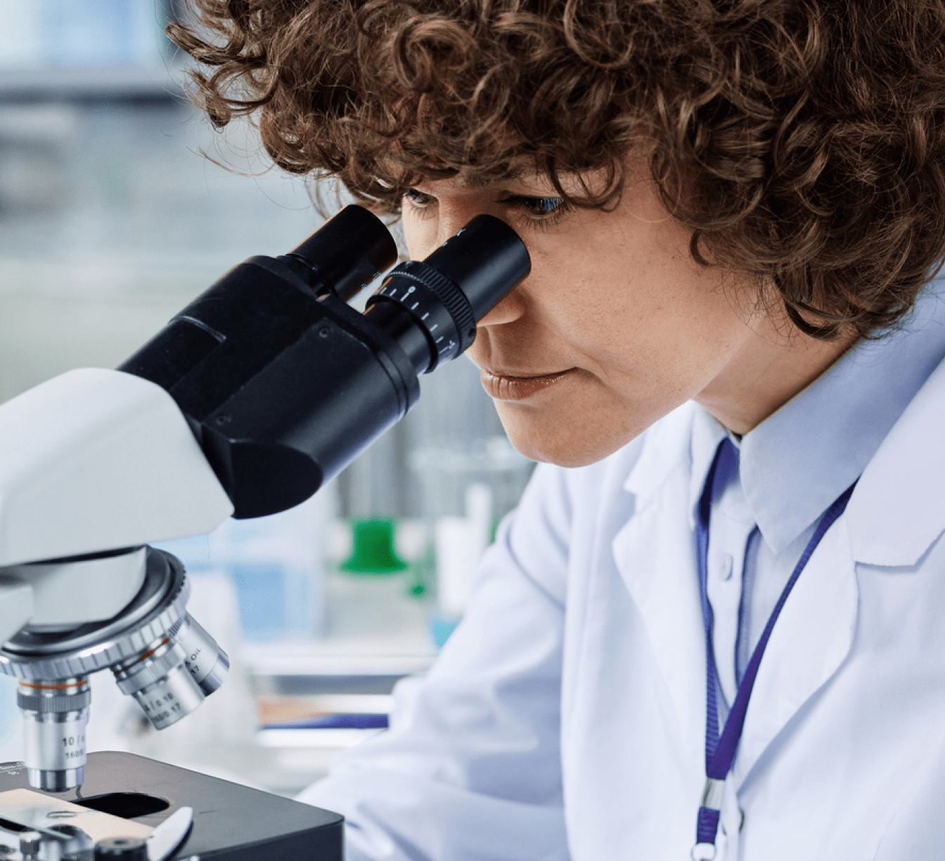 Scientists looking into a microscope at a microscope slide