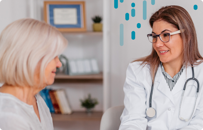A medical professional wearing a stethoscope smiles at a patient during a consultation