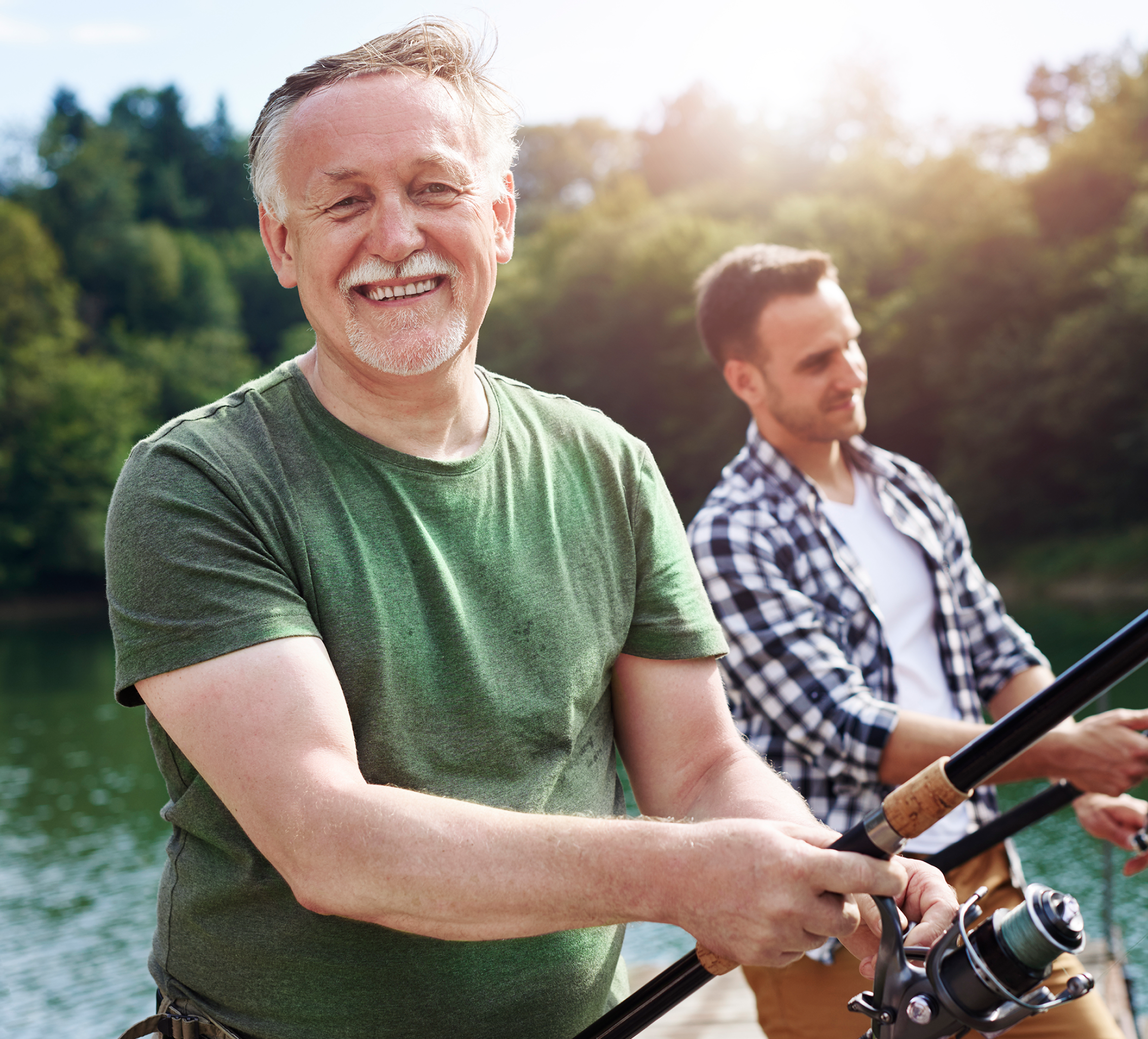 A happy older man fishes with his son